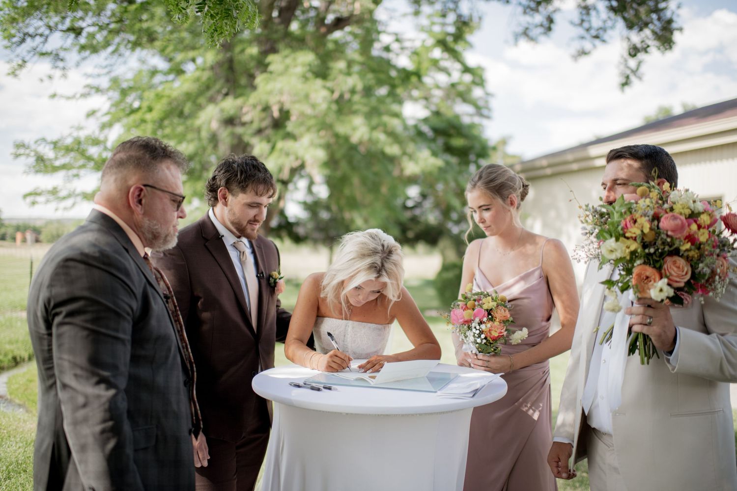 Wedding ceremony guests gather at an outdoor garden venue signing documents and celebrating the special occasion.