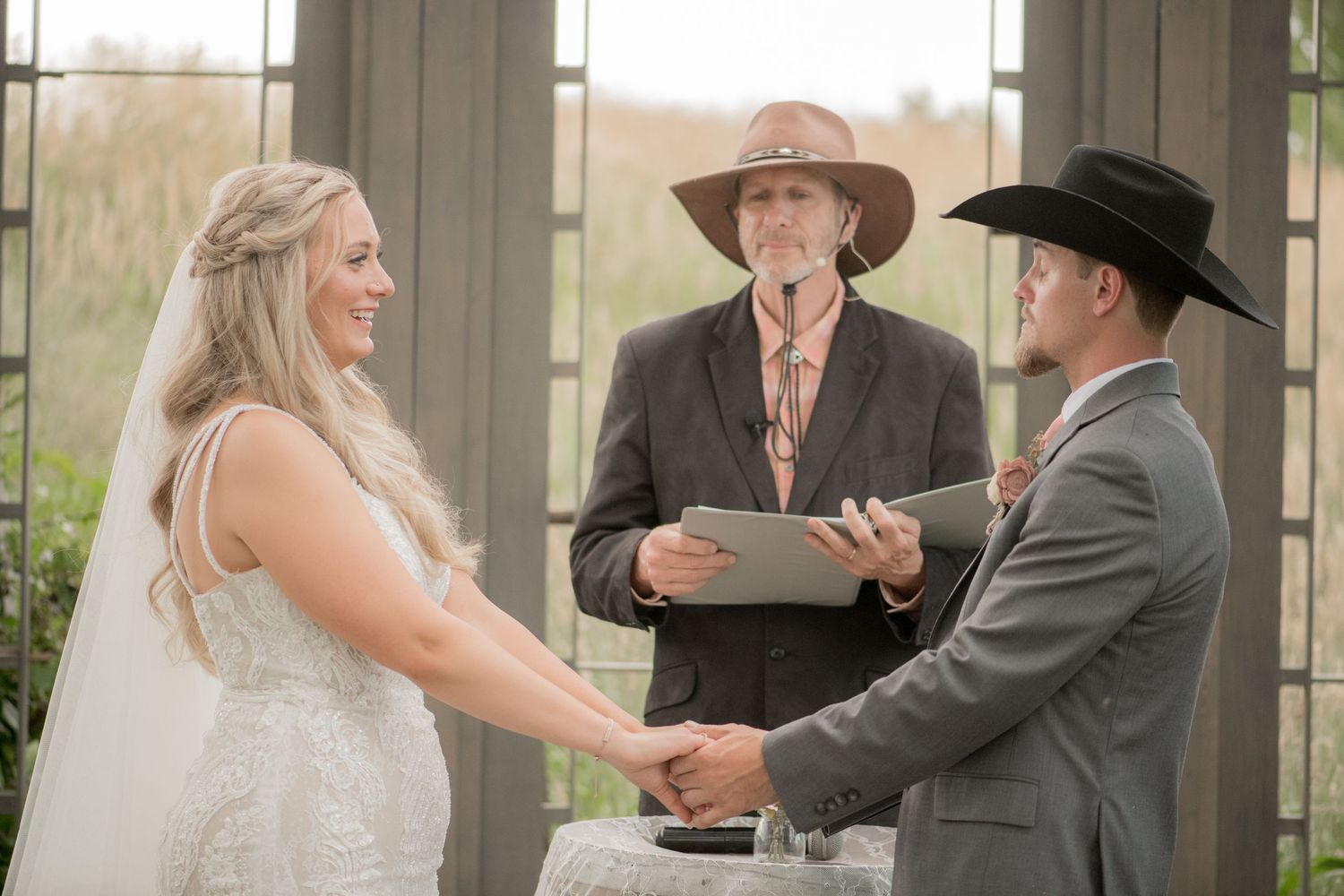 A bride and groom share a tender moment during their wedding ceremony under a covered outdoor venue.