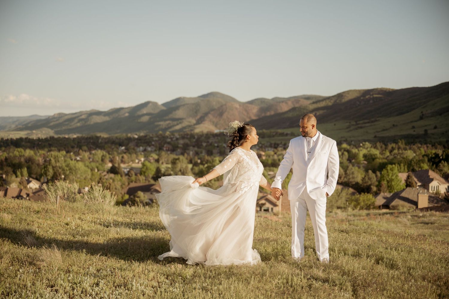 A scenic wedding portrait captured in the desert with mountains in the background during golden hour.