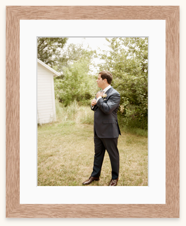 A photographer in a suit captures photos in a rustic outdoor setting with wooden frames in the background.