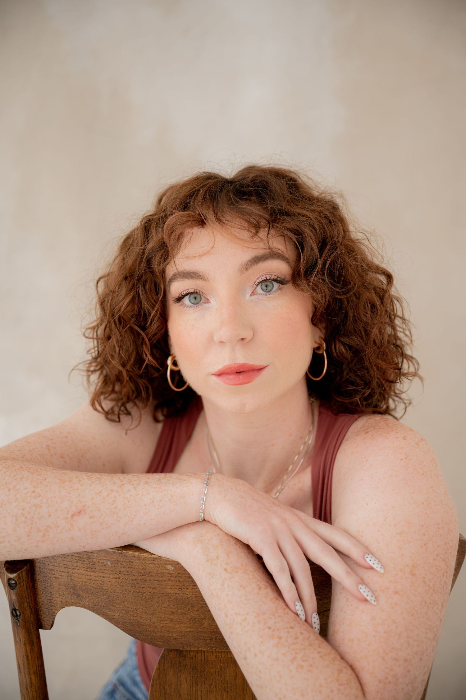 A series of four photos showing someone with curly red hair and freckles posing against a neutral background.