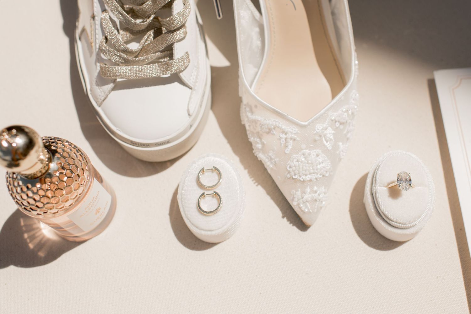 White sneakers and wedding rings arranged in a creative flat lay composition with soft lighting and shadows.
