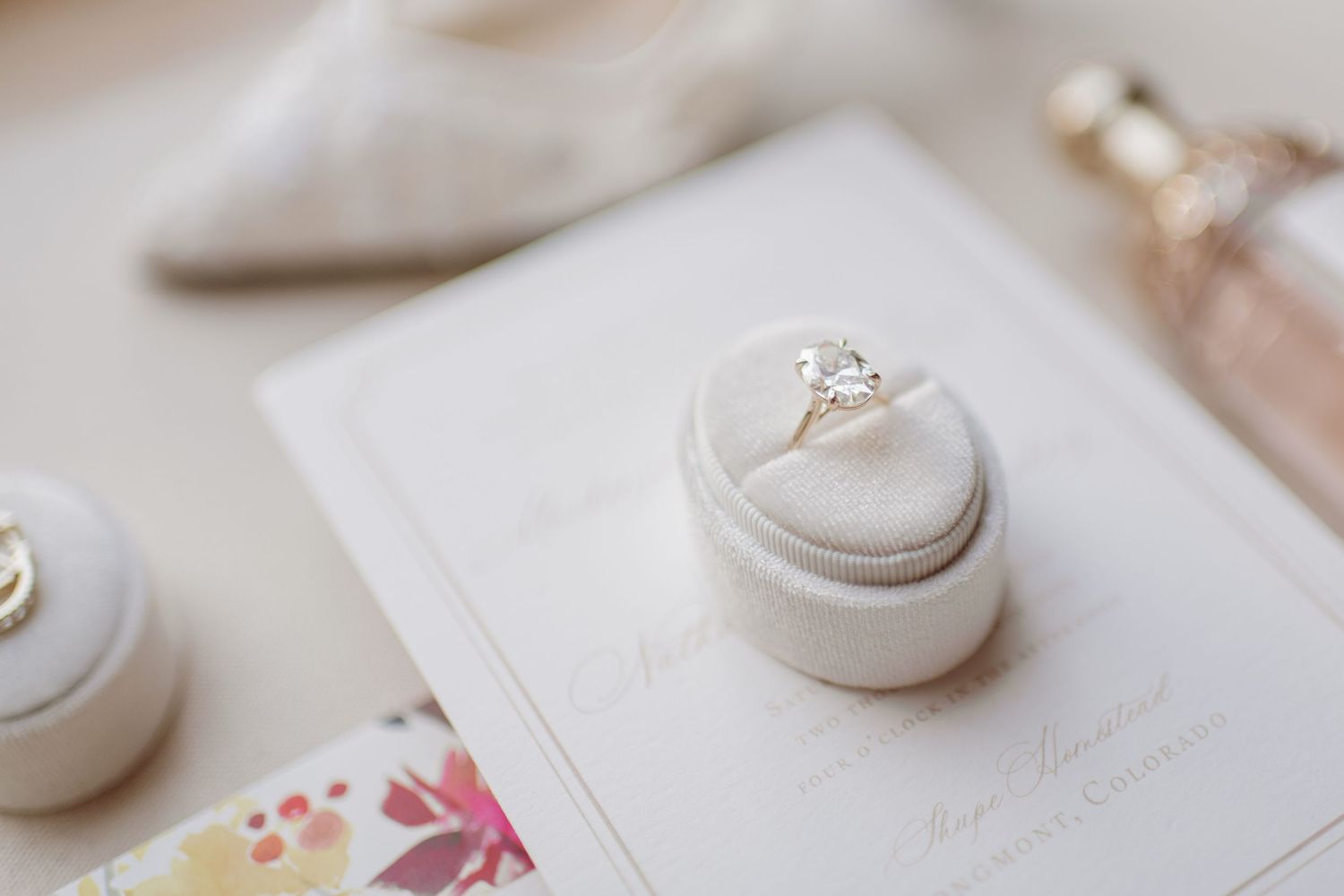 Delicate white porcelain ring boxes with floral designs and gold accents arranged on a light beige surface.
