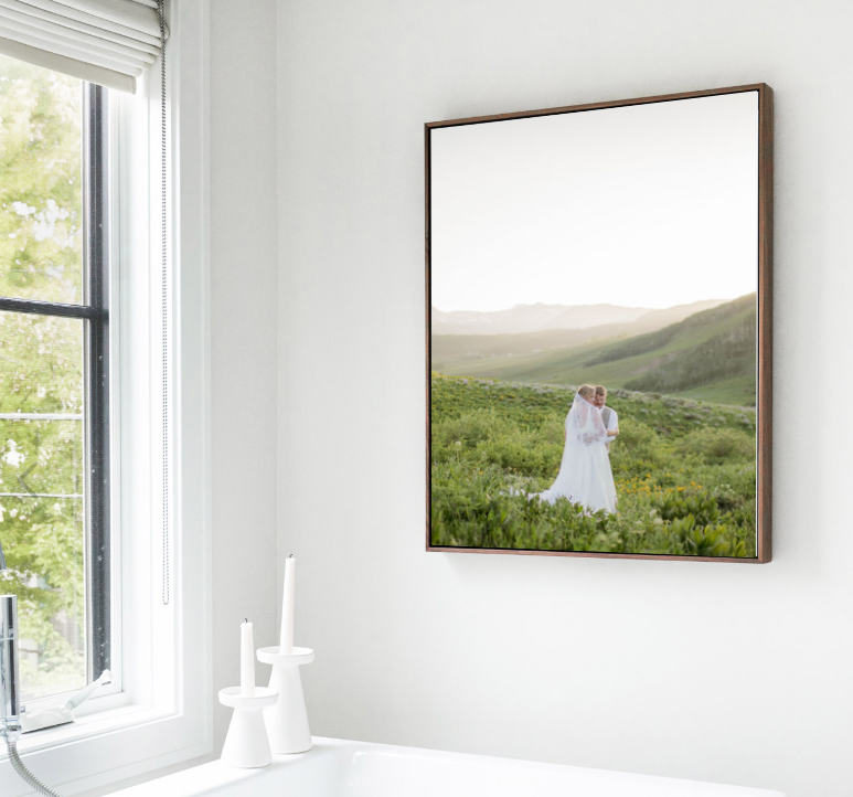 A series of framed landscape photographs with a figure in white displayed on a bright white wall in a modern interior.
