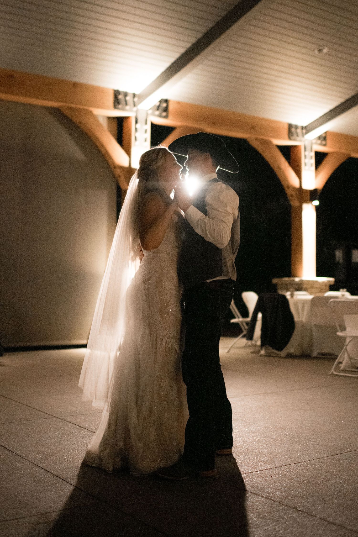 A romantic sequence of wedding photos showing a couple dancing together in a dimly lit venue with dramatic lighting.