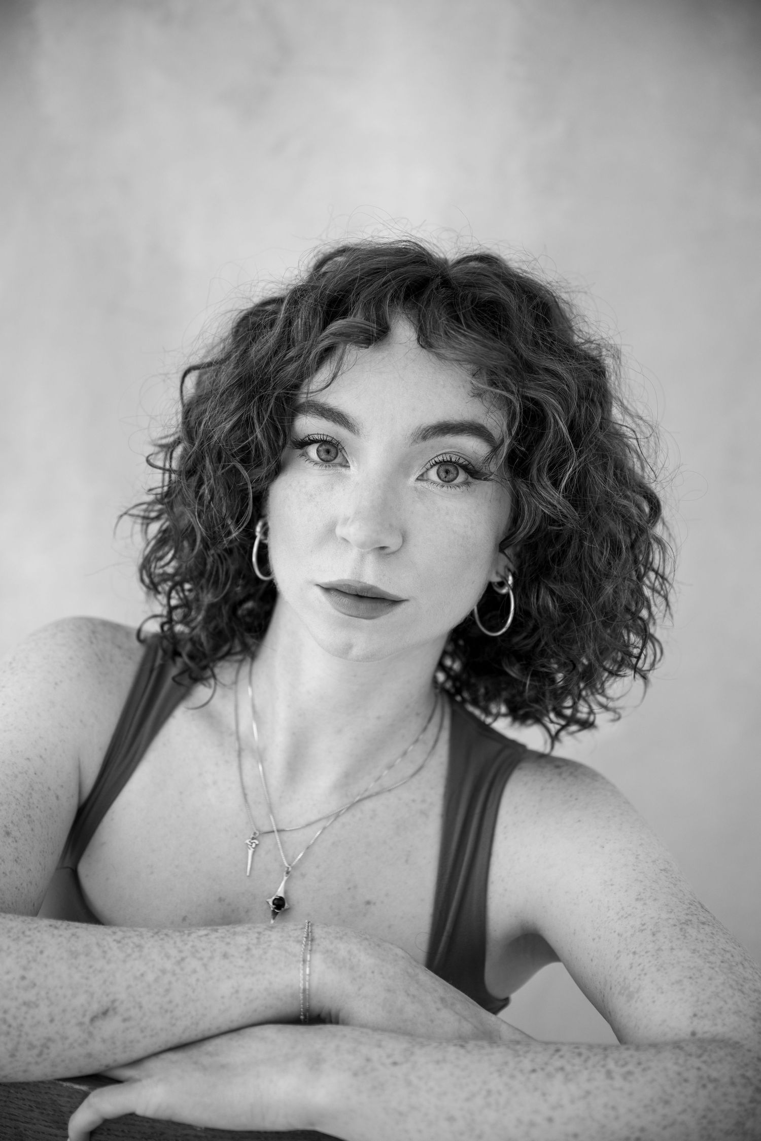 A black and white photo series showing a person with curly dark hair posing in artistic portraits.