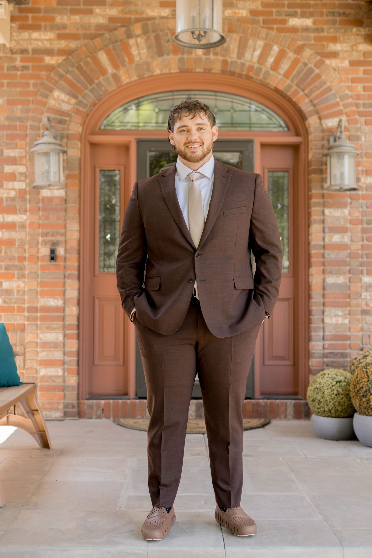 Four sequential photos showing someone in a brown suit standing on a brick porch with arched doorways and decorative planters.