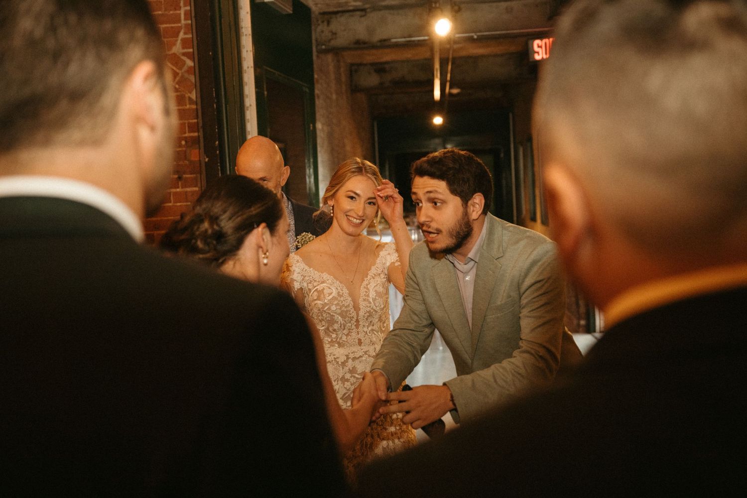 A couple shares an intimate moment during their wedding ceremony in a dimly lit rustic venue.