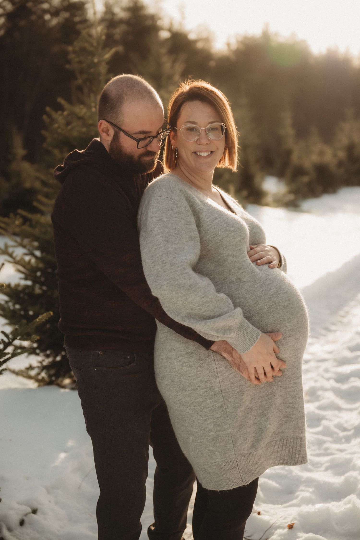 Expecting couple shares tender moment during winter maternity photoshoot in snow.