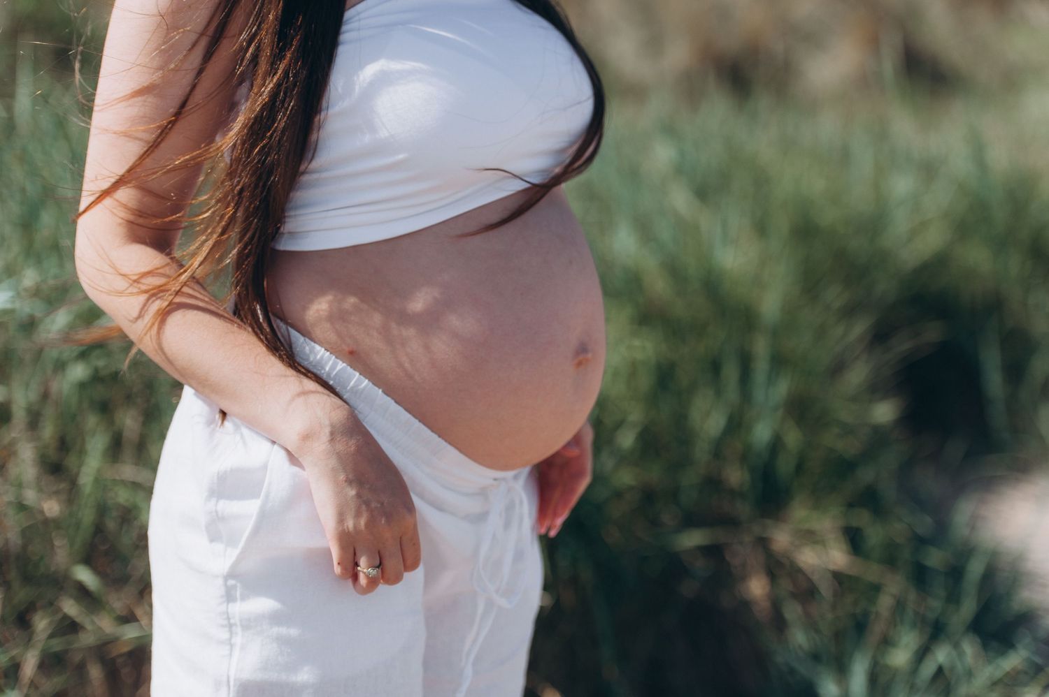 Little one gently touching mom’s pregnant belly in soft light