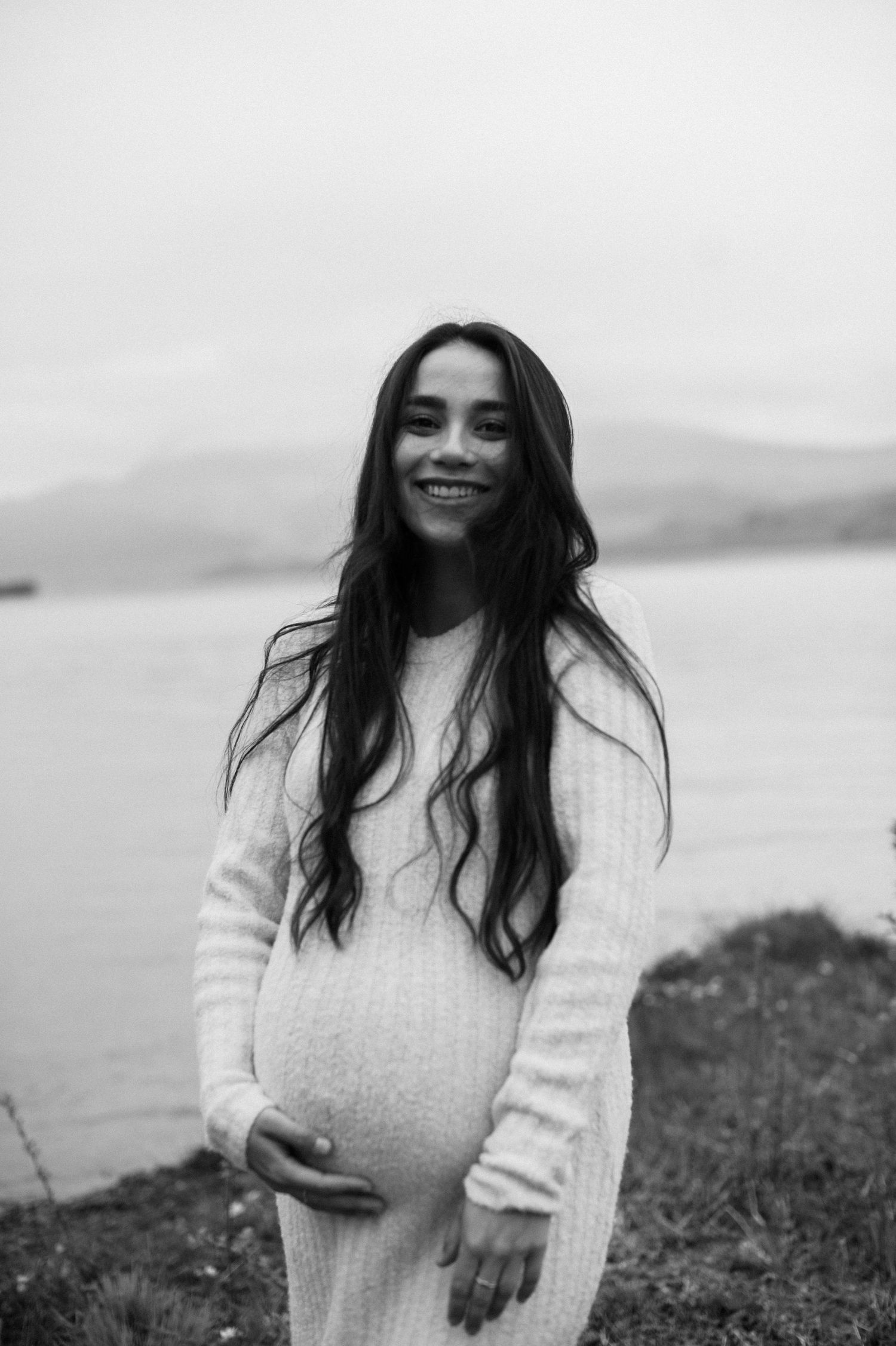 Little one gently touching mom’s pregnant belly in soft light