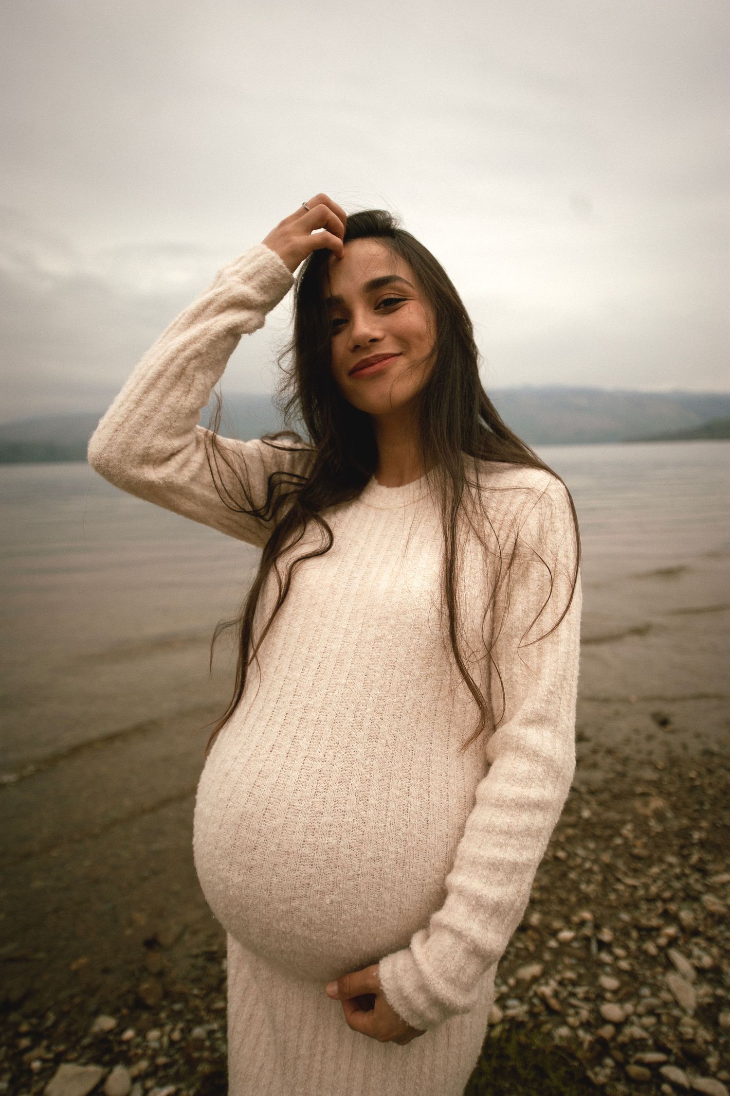 Little one gently touching mom’s pregnant belly in soft light