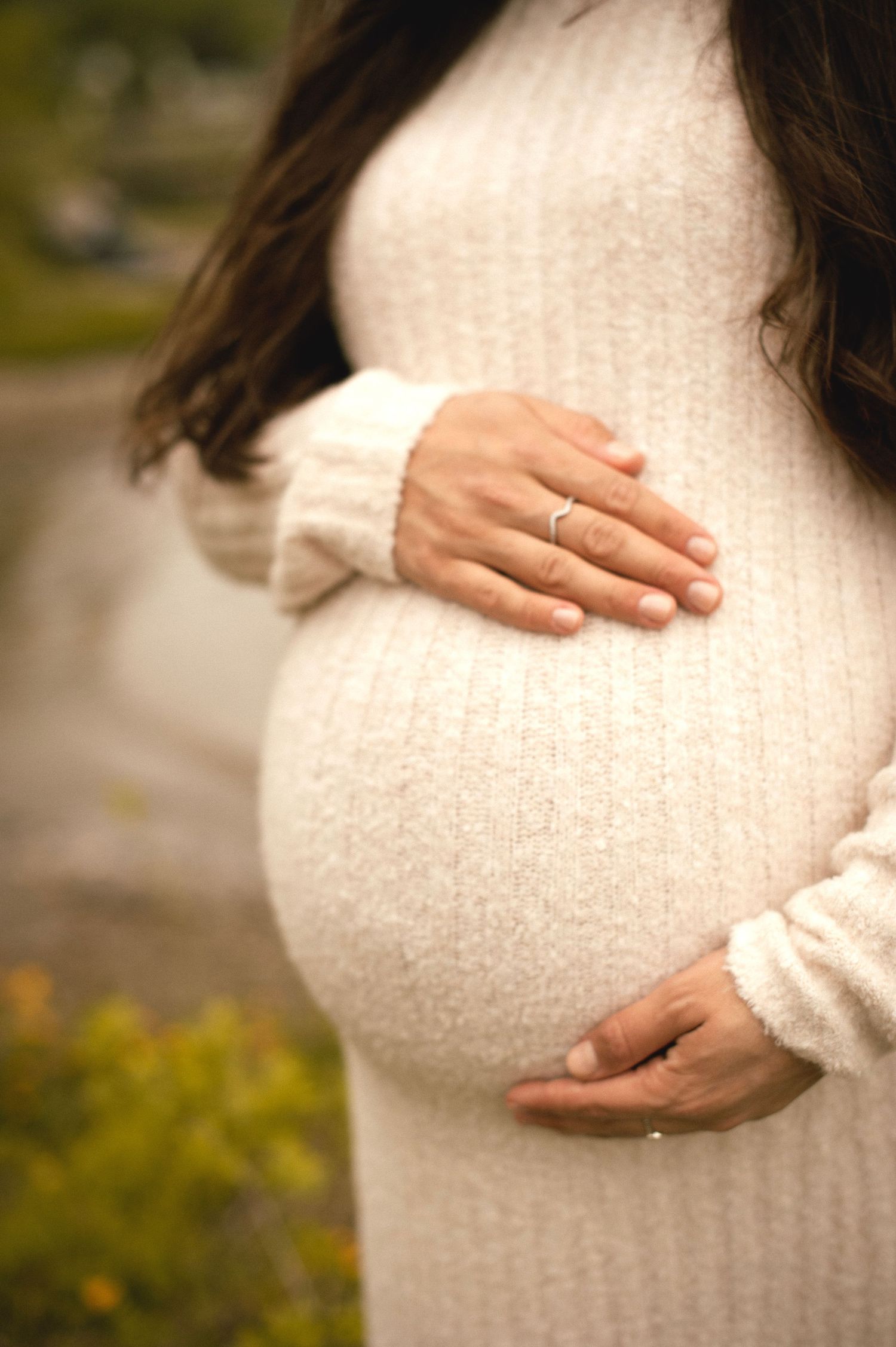 Little one gently touching mom’s pregnant belly in soft light
