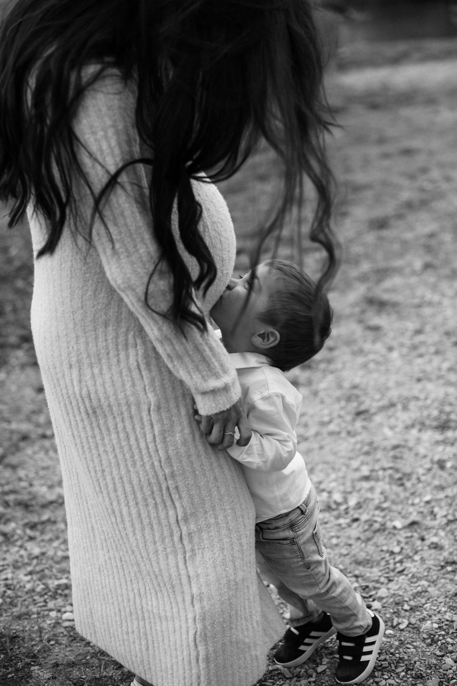 Little one gently touching mom’s pregnant belly in soft light