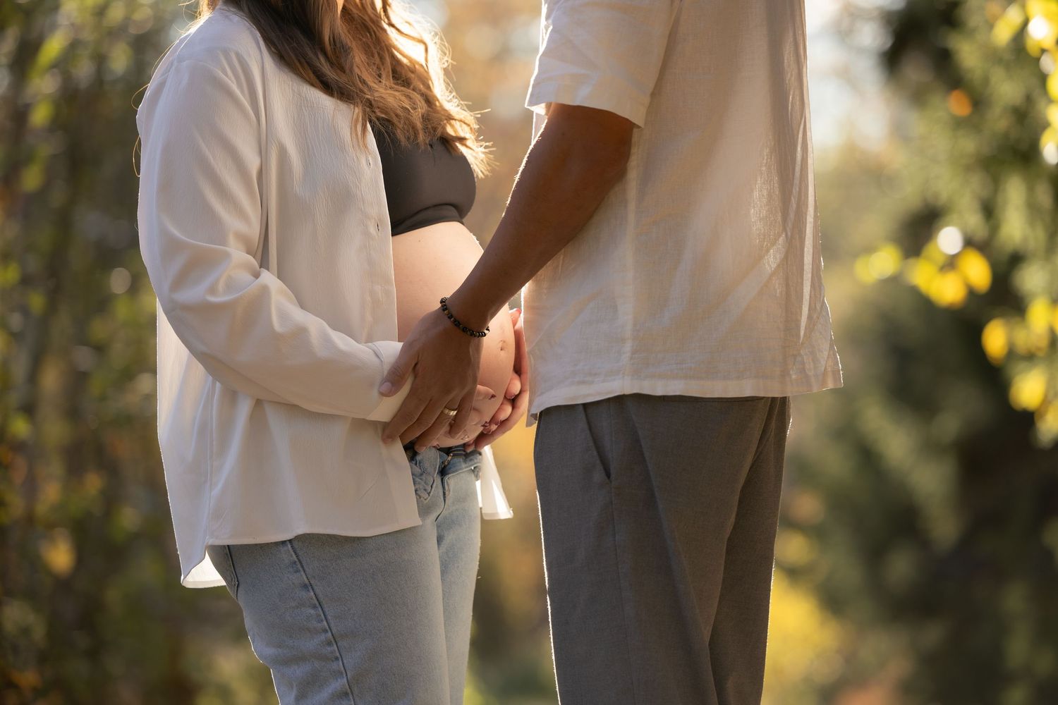 Couple holding hands in casual attire during sunset.