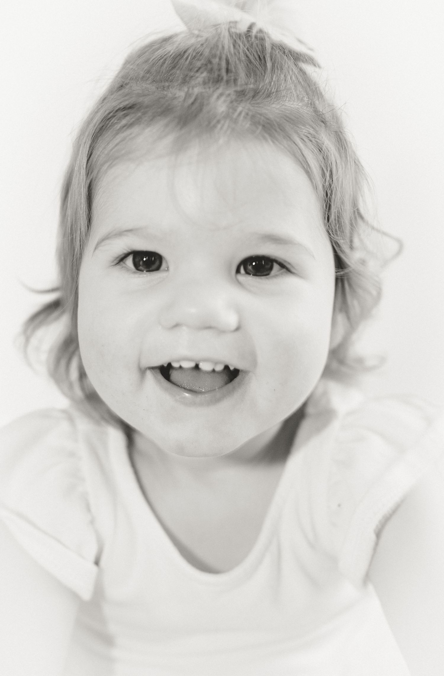 Black and white portrait series showing close up expressions and playful smiles of a young child.