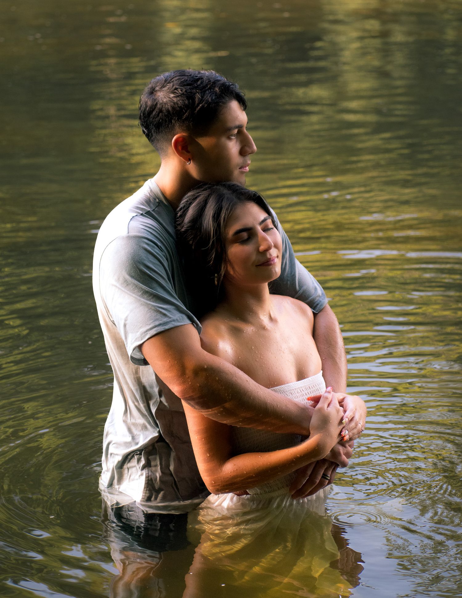 Romantic water photoshoot with couple embracing in gentle waves.
