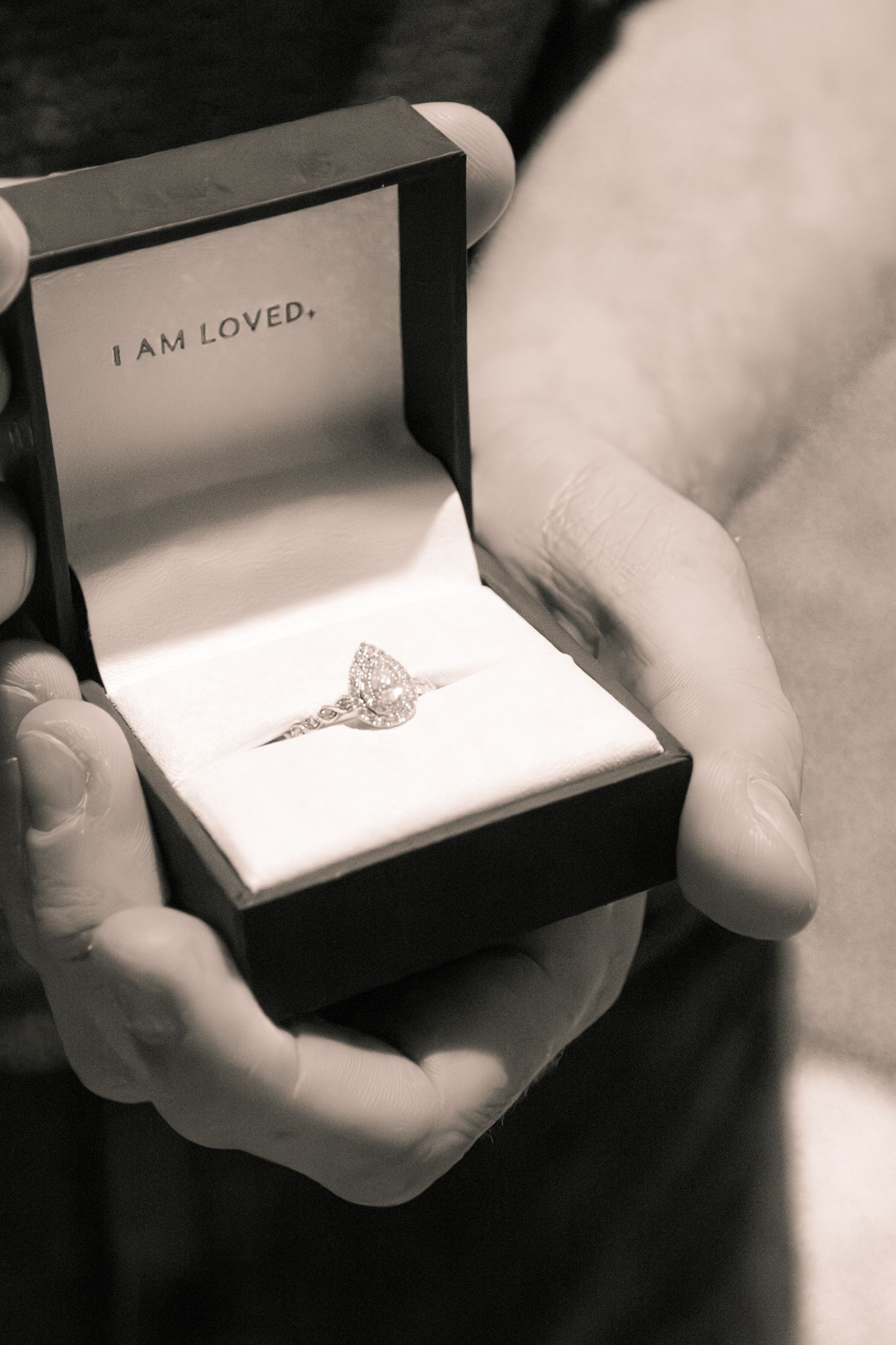 Close-up black and white photo of an elegant diamond engagement ring on a velvet box