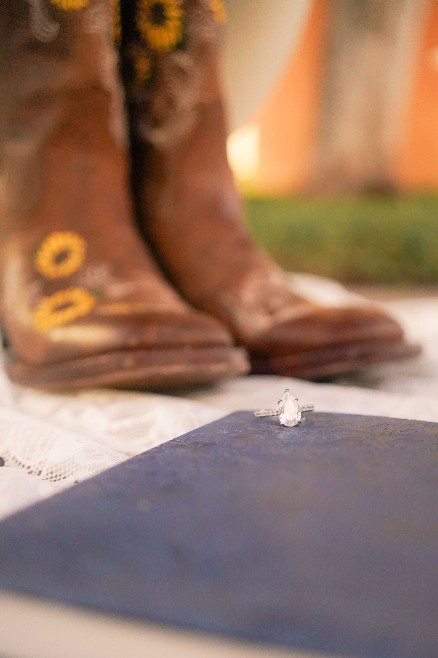 Close-up of embroidered brown cowboy boots with a ring on blue surface.