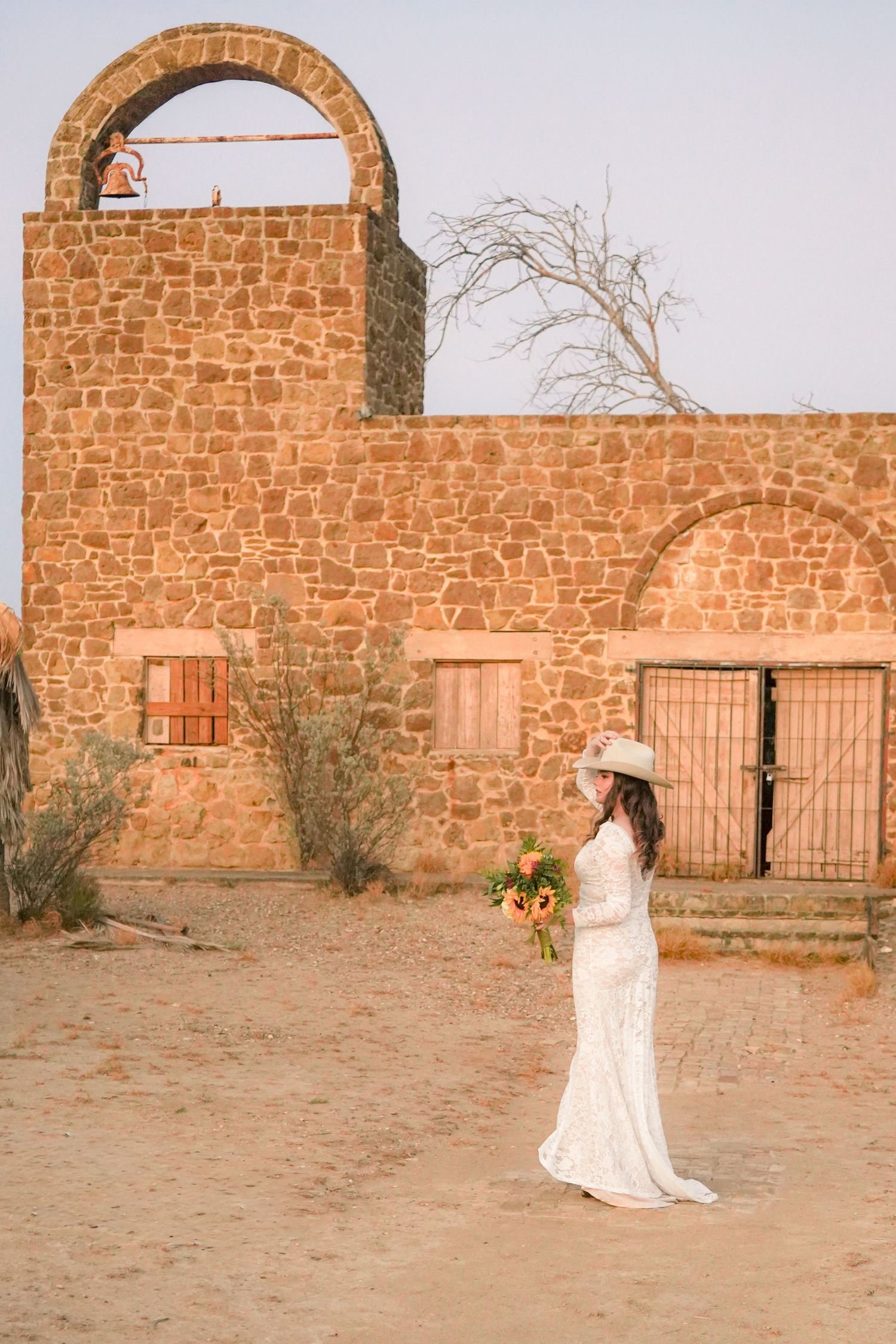 White wedding dress against rustic stone ruins in desert setting.