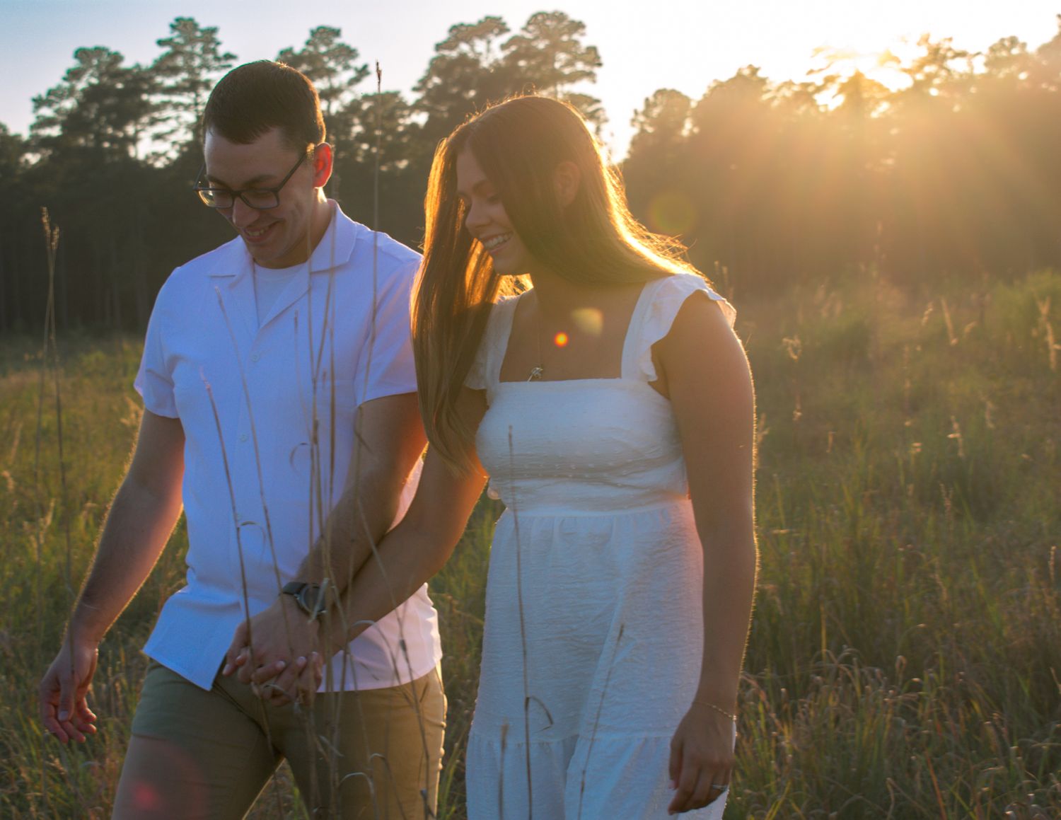 Sunset engagement session in field with warm golden lighting.