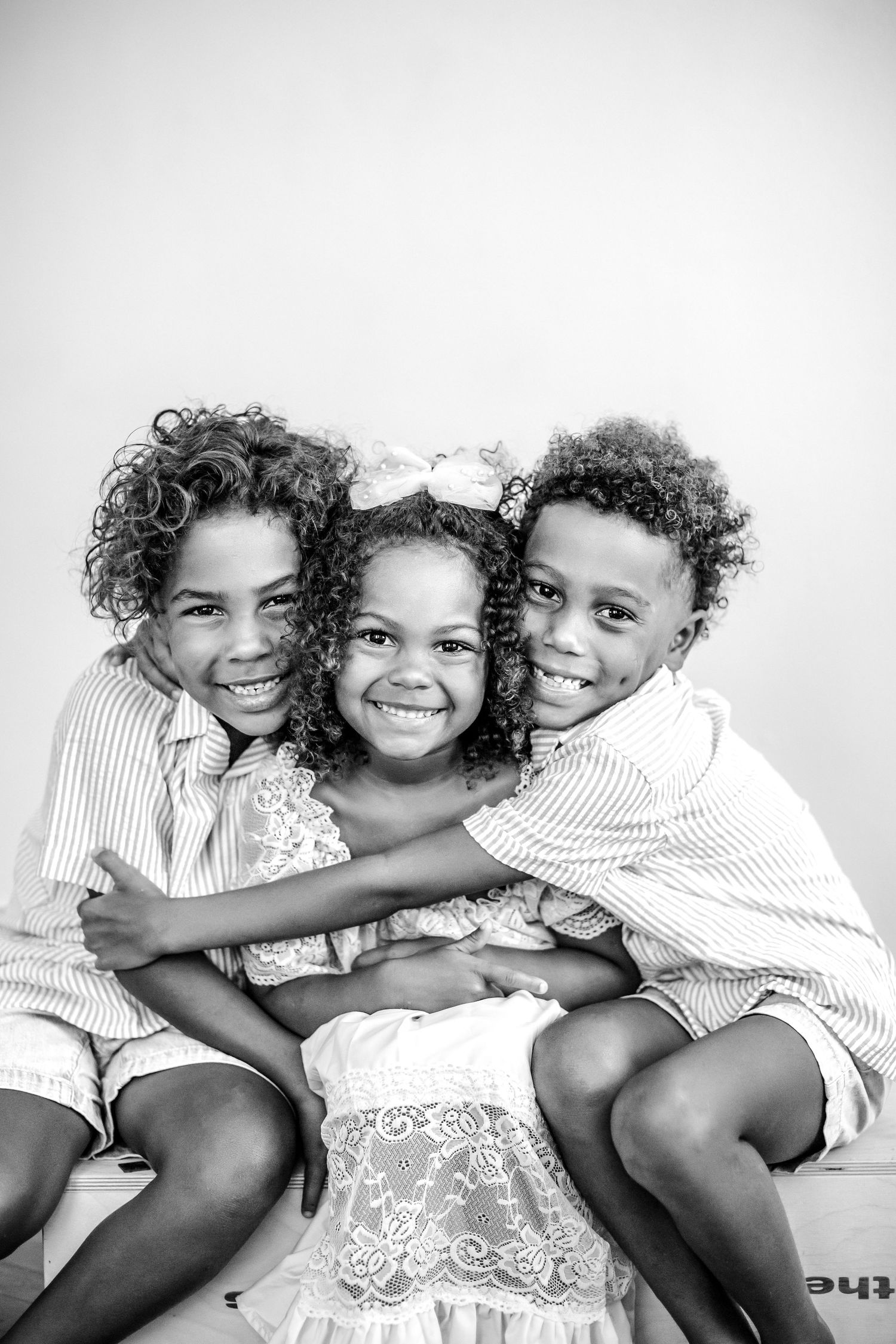 Three siblings hugging during their Petite Personality Portrait Session in Bradenton, Florida's Tierney House.