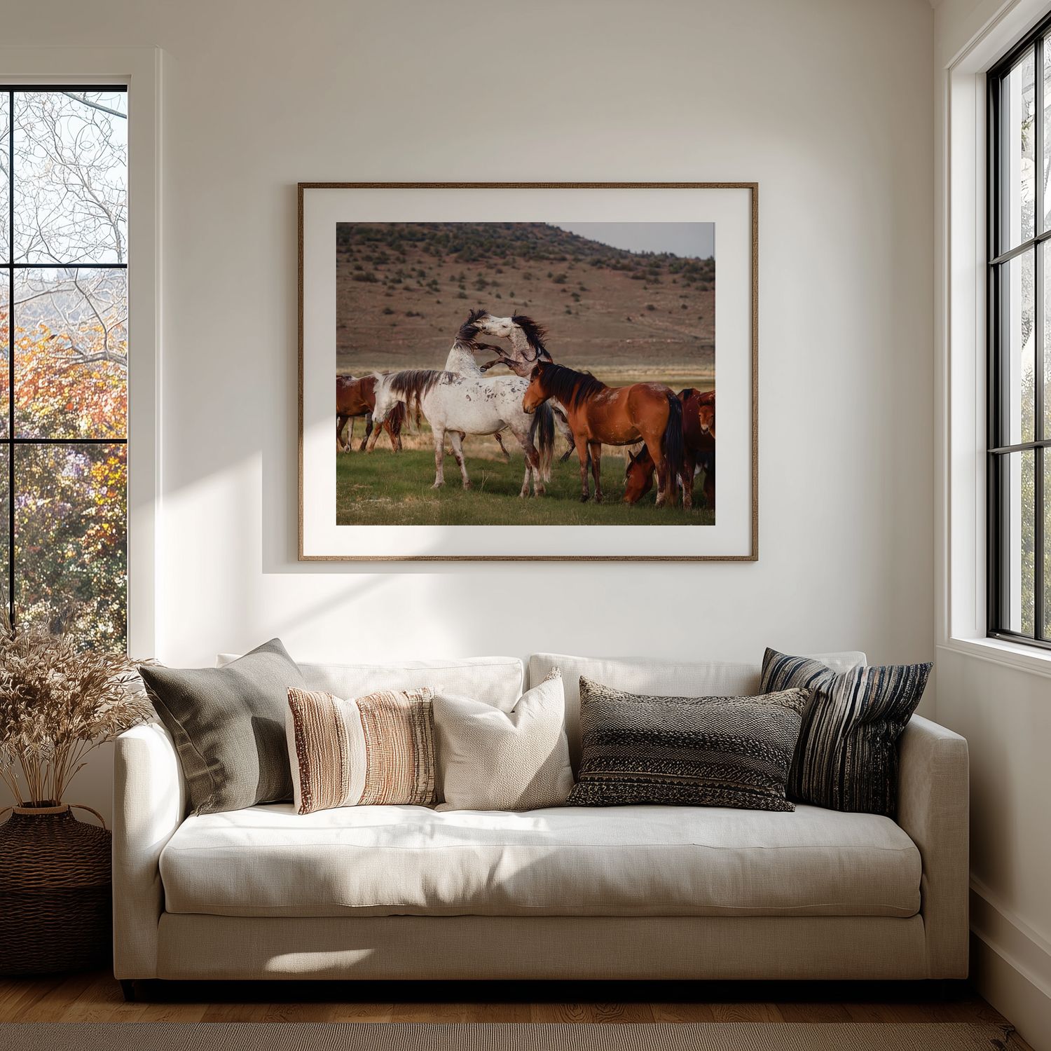 A series of five framed landscape photographs displayed on a white wall above a modern gray couch in natural light.