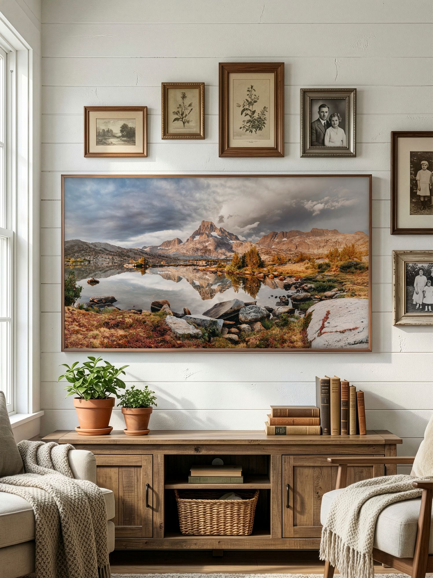Cozy living room wall decorated with landscape panoramas, framed artwork, and rustic wooden furniture.