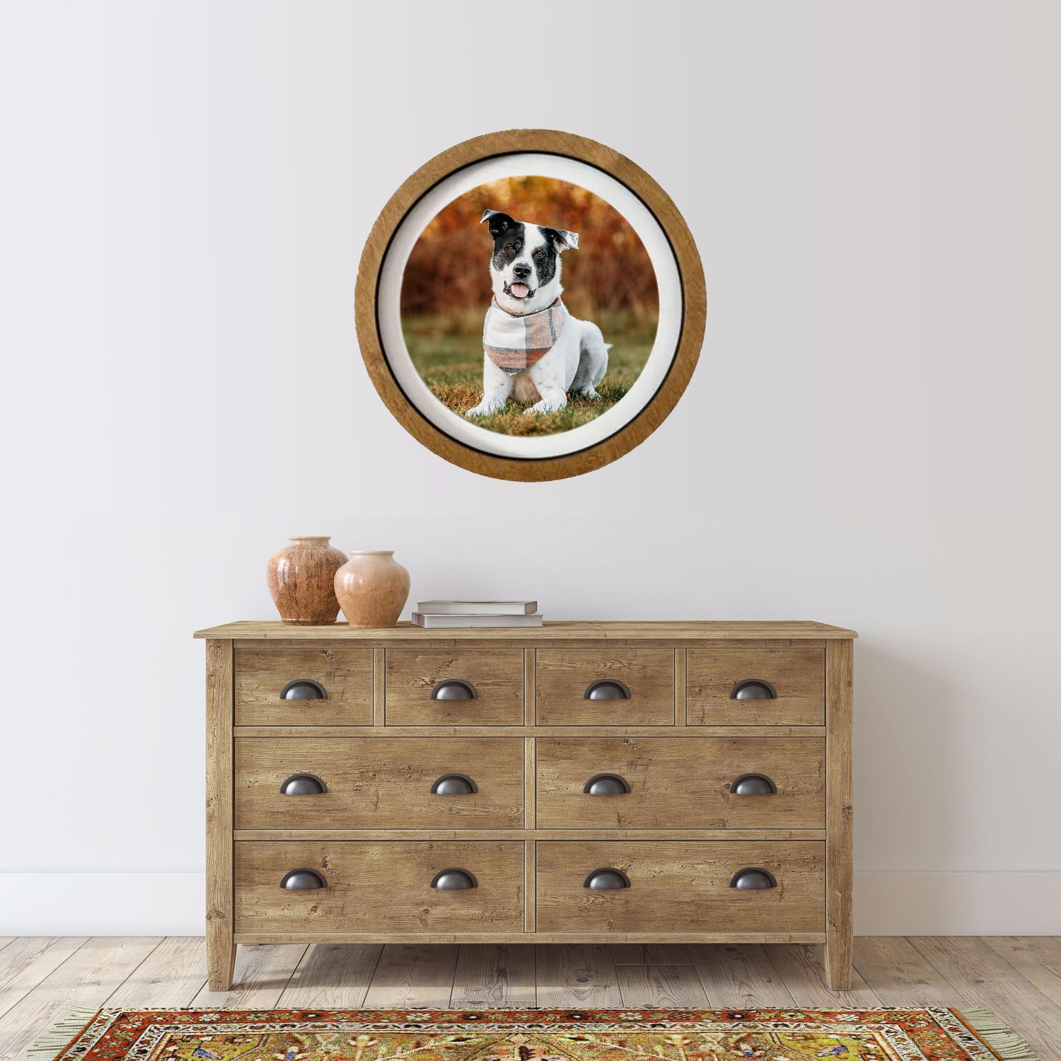 Rustic wooden dresser with oval framed artwork displayed on white wall in minimalist interior setting.