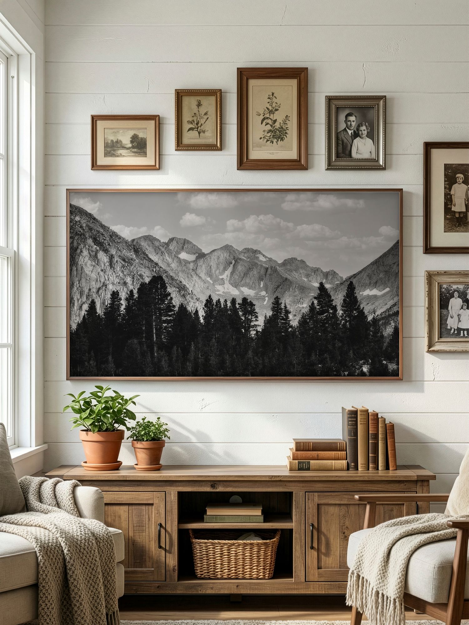 Cozy living room with black and white mountain landscape artwork above wooden media console and vintage wall gallery.