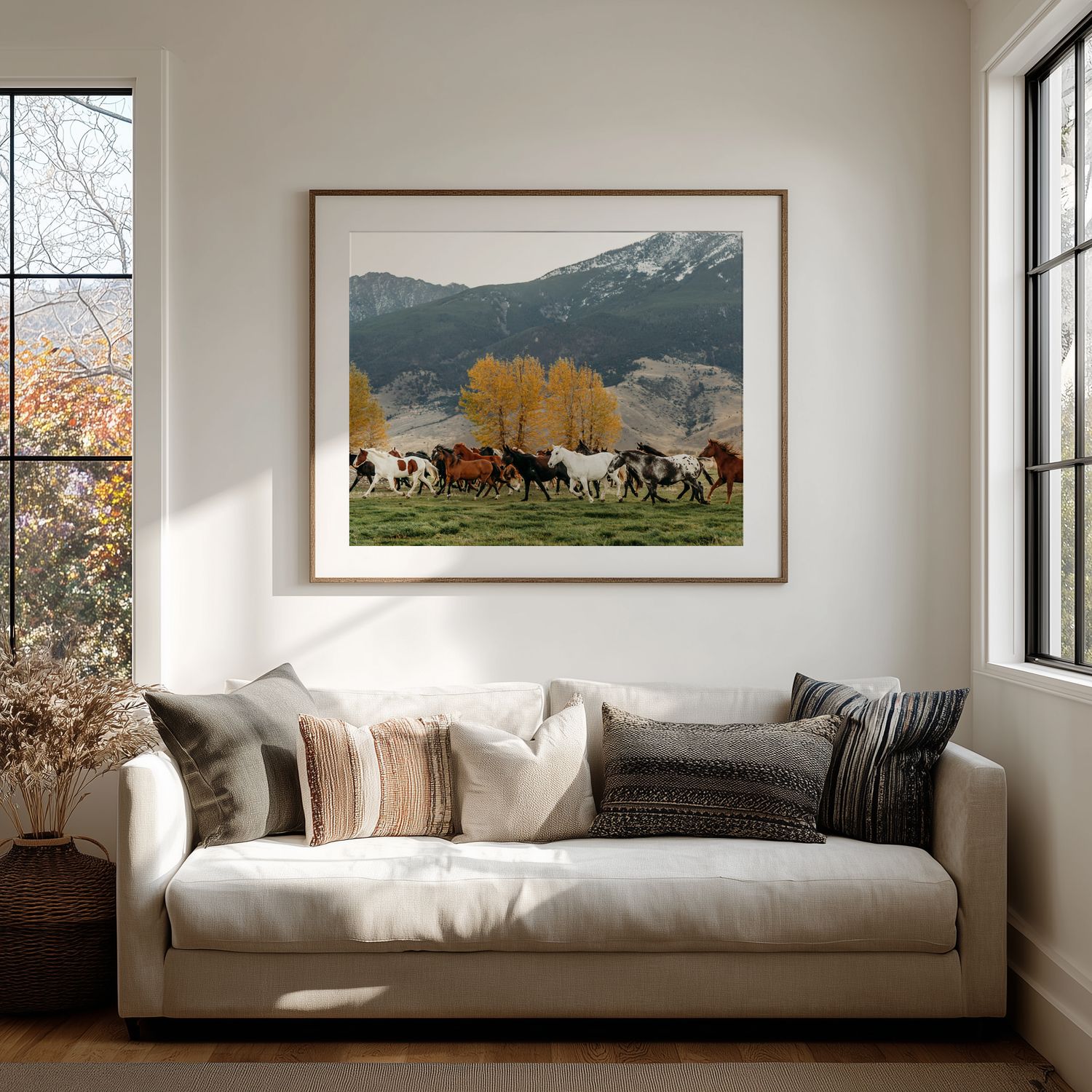 Modern living room with panoramic landscape photographs above a white couch against white walls.