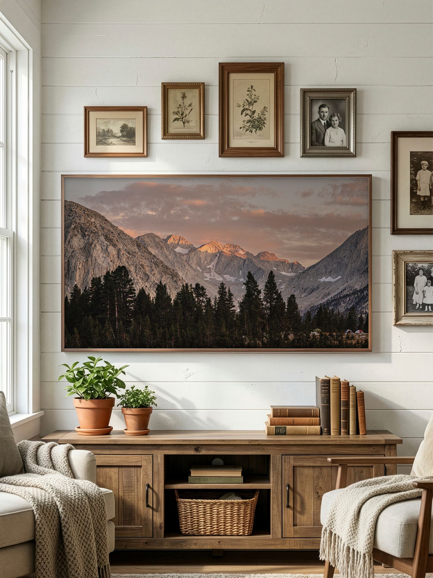 A cozy living room with mountain landscape artwork, white shiplap walls, and rustic wood furniture creates a warm atmosphere.