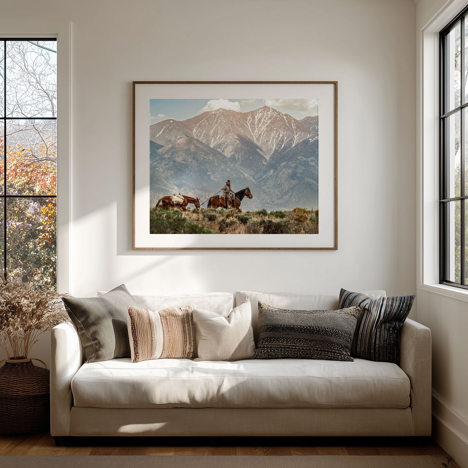 Panoramic landscape photographs adorn white walls above a modern gray sofa in a minimalist living room interior.