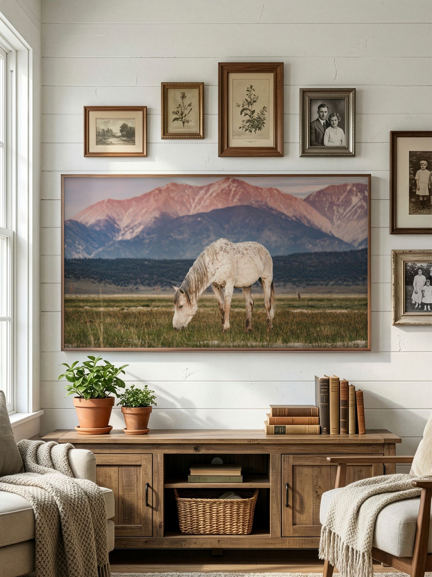 Living room interior featuring wide landscape photographs of mountains and wild horses above rustic wooden furniture.