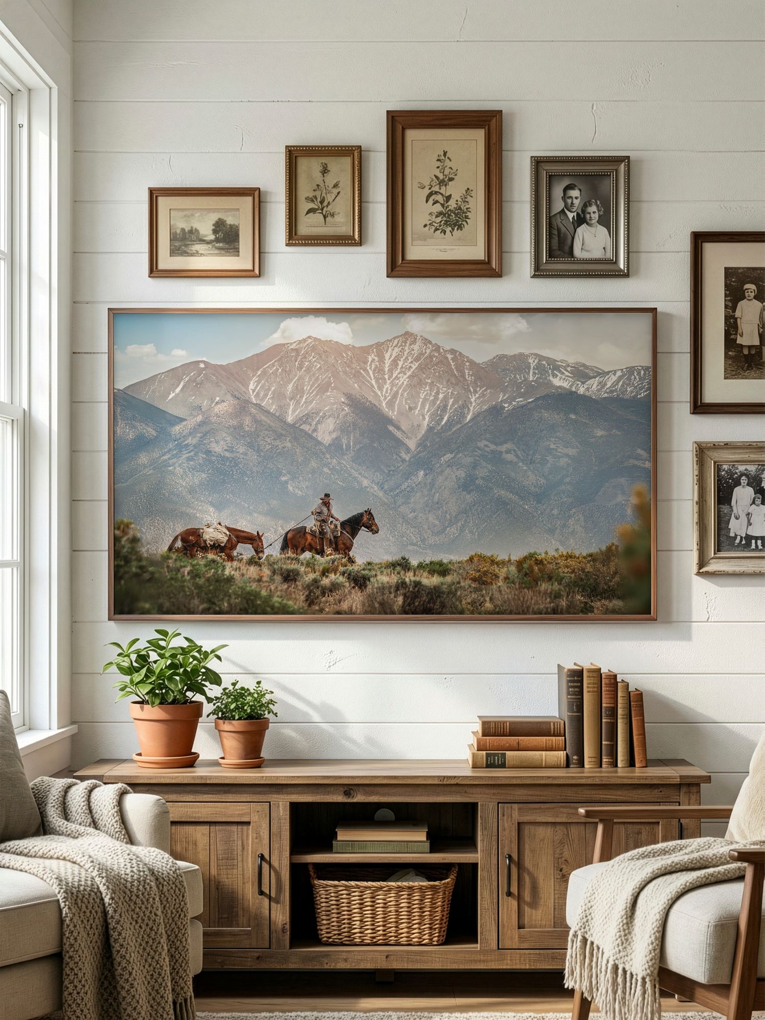 Panoramic landscape paintings of mountains and horses hang on white shiplap walls above a rustic wooden console table.
