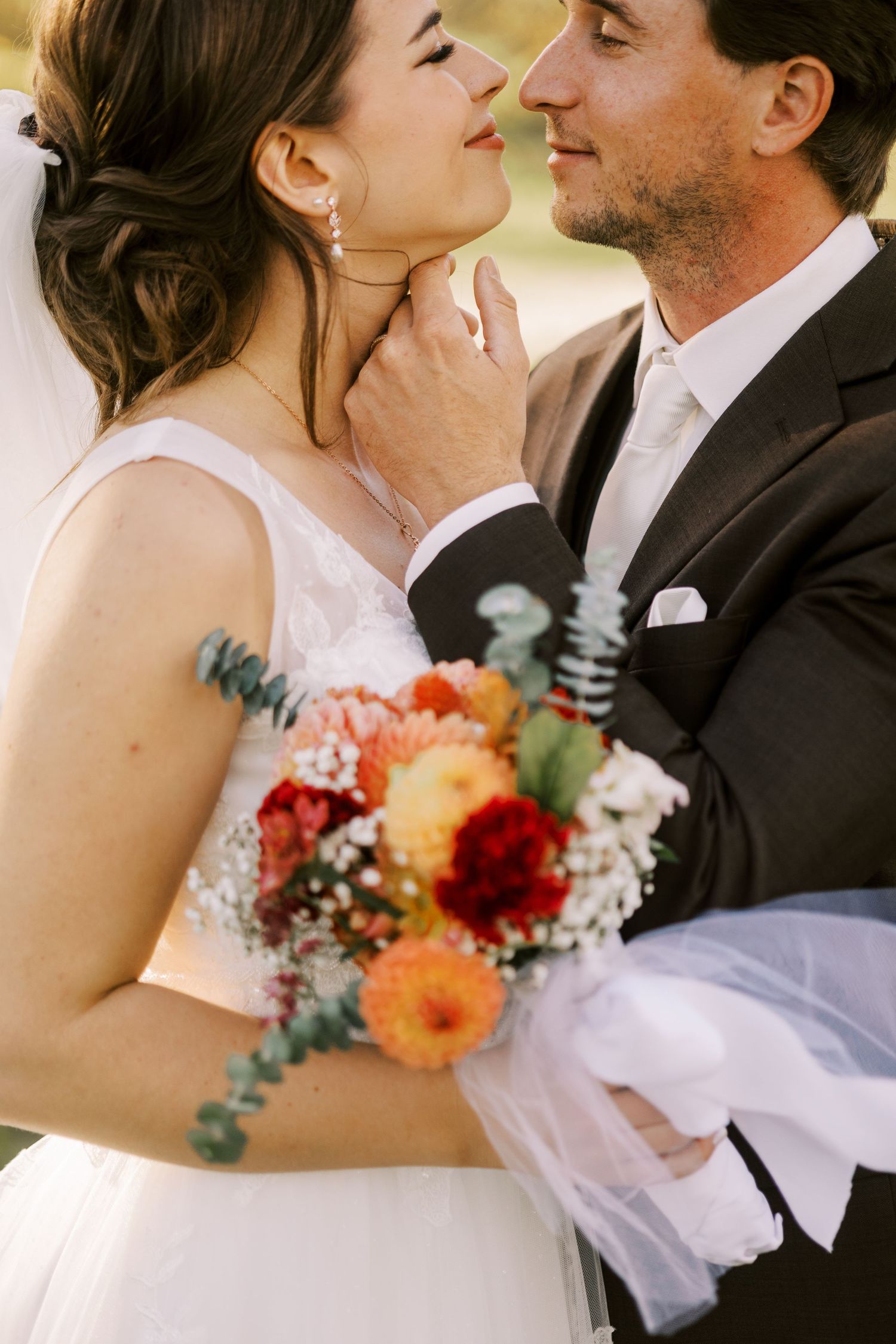 A romantic close-up of newlyweds sharing an intimate moment with a colorful bouquet.