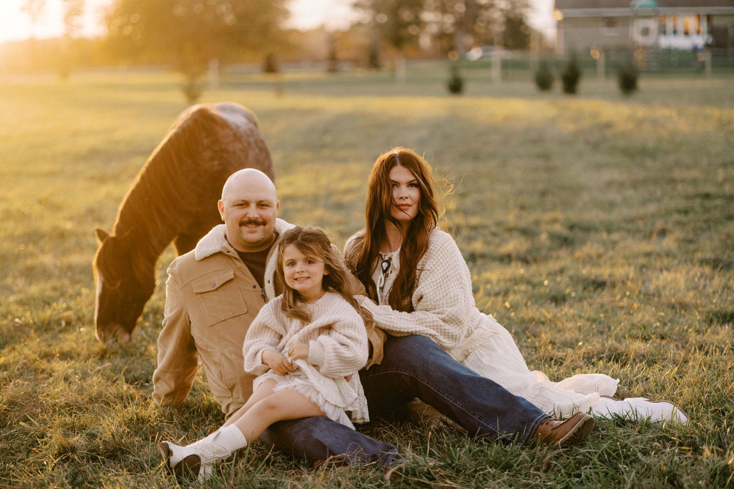 A family relaxing together on grass during golden hour sunset.