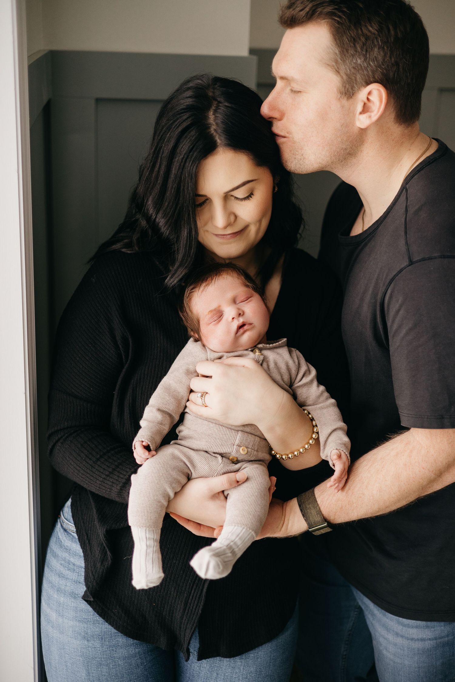 Intimate family moment with parents holding their sleeping newborn baby.