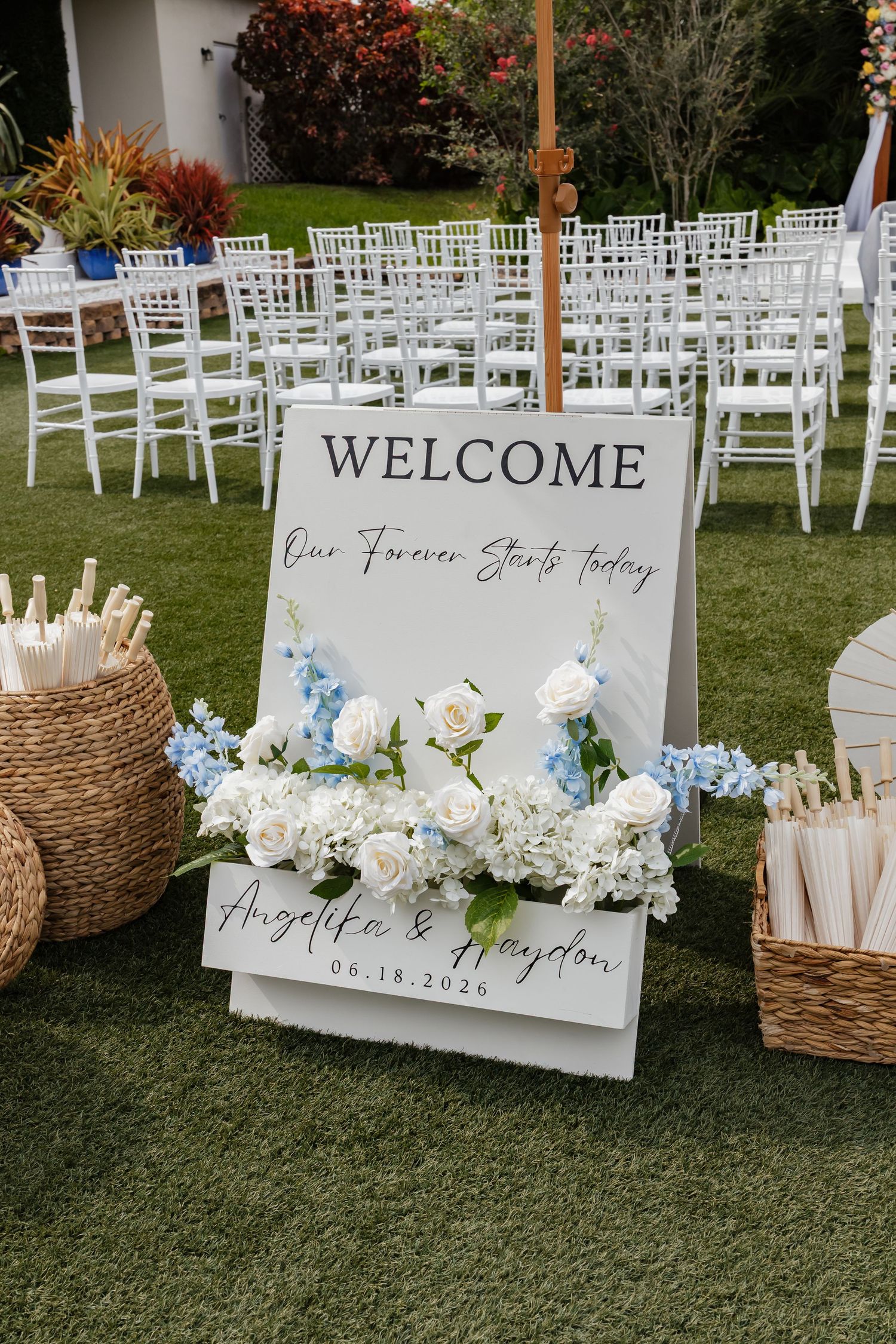 Wedding welcome sign for Angelika and Haydon 06-18-2026 adorned with white and blue flowers.