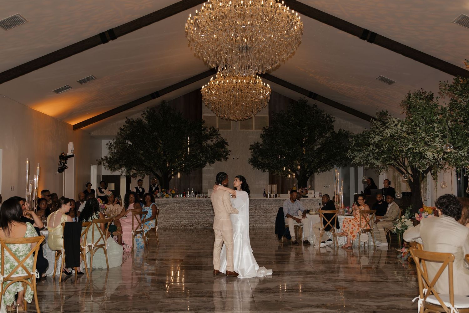 Couple sharing their first dance under a grand crystal chandelier in an elegant wedding reception venue.