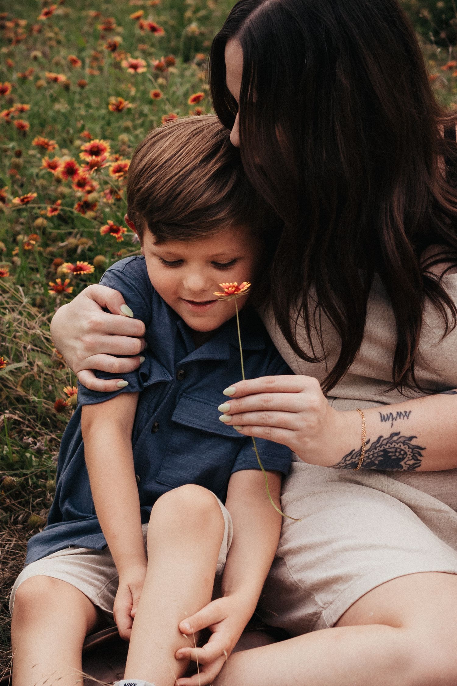 A tender embrace shared in a field of orange wildflowers on a sunny day.