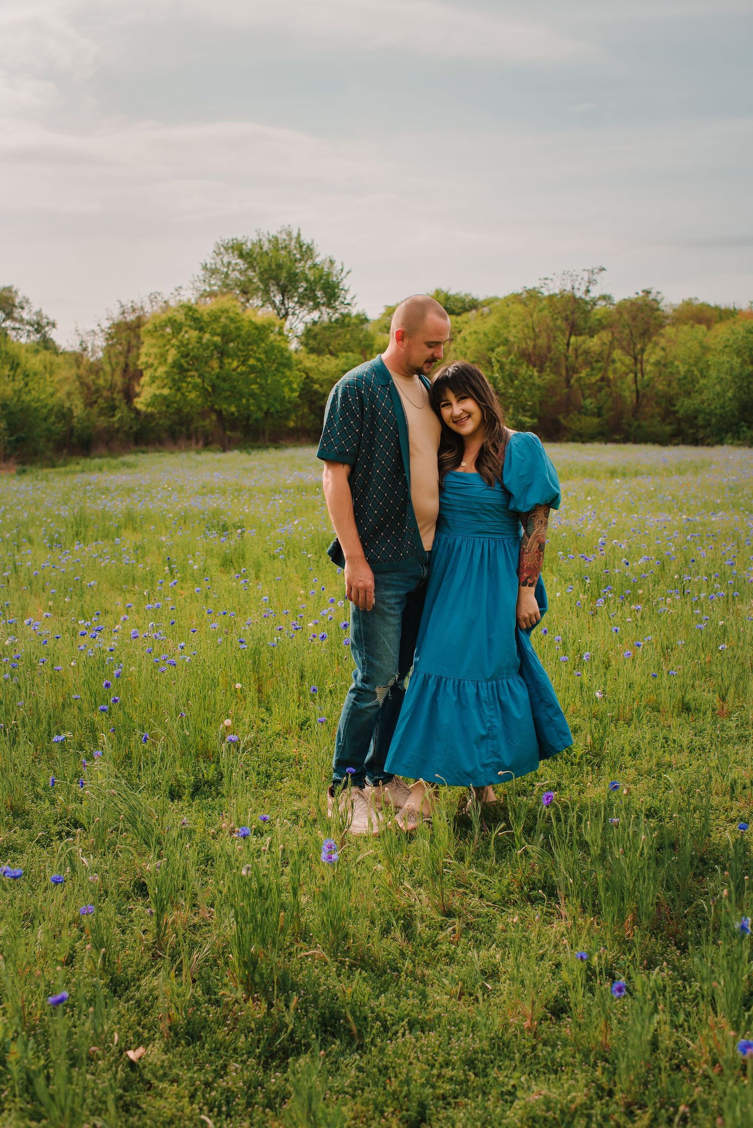 Couple standing together in blooming wildflower meadow at sunset.
