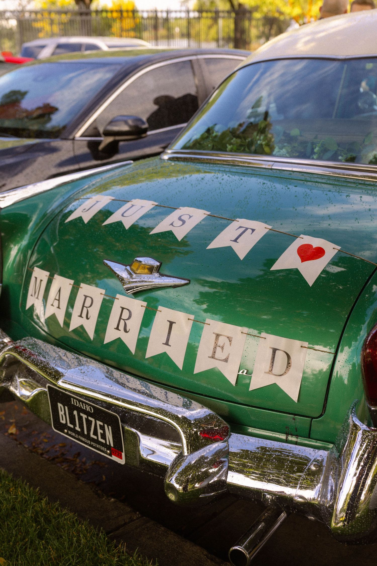 Vintage green car decorated with Just Married bunting banner and Blitzen license plate at a wedding celebration.