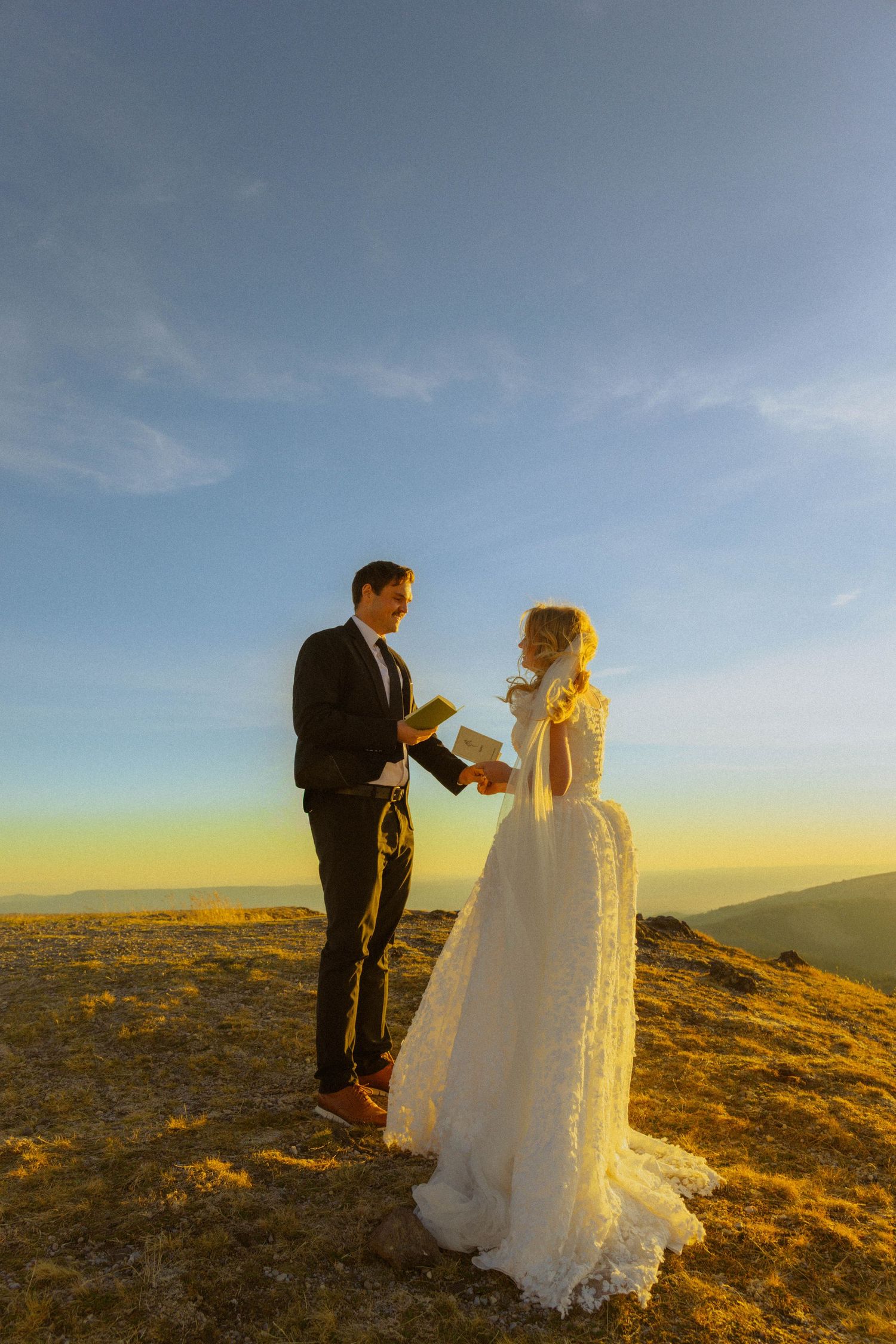 Bride and groom exchange vows on a mountain summit at golden hour sunset in a romantic outdoor wedding ceremony.