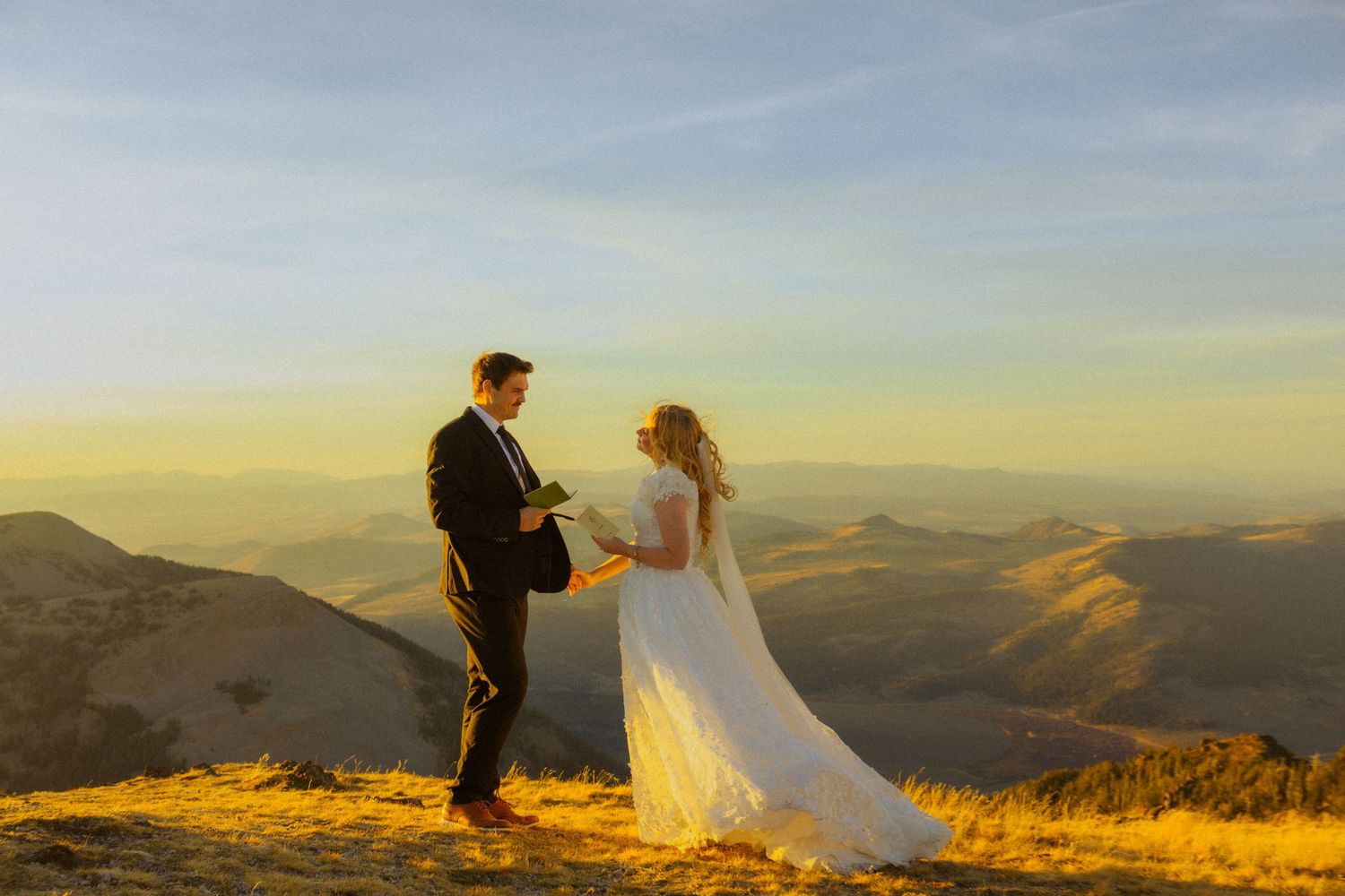 Couple exchanging vows at golden hour on a mountain summit with sweeping valley views.
