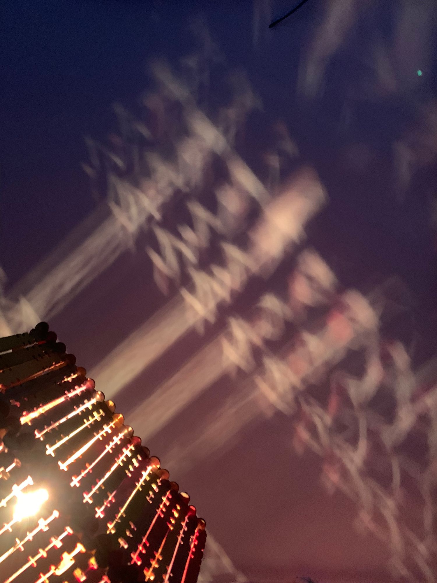 A long exposure night shot of illuminated building lights creating abstract streaking patterns against dark sky.