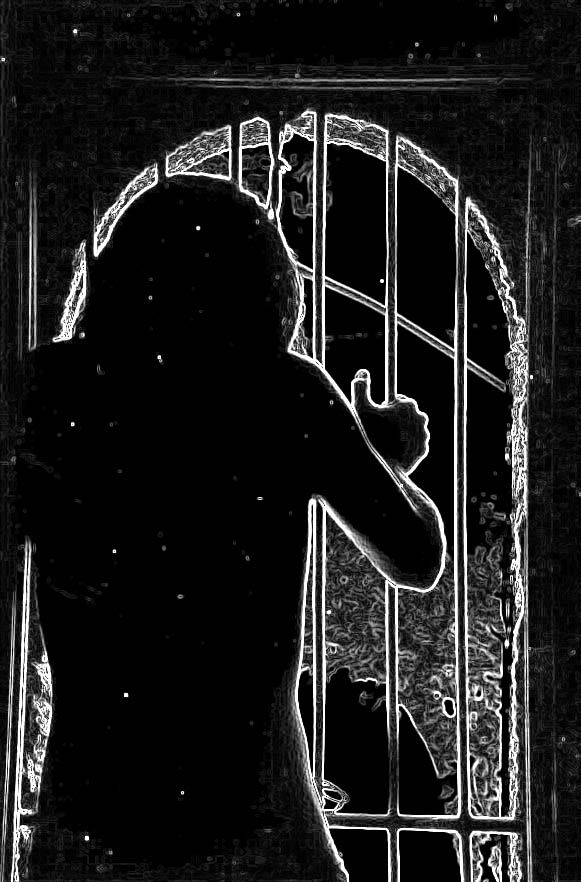 A high contrast black and white silhouette of a person standing at an ornate arched window gate.