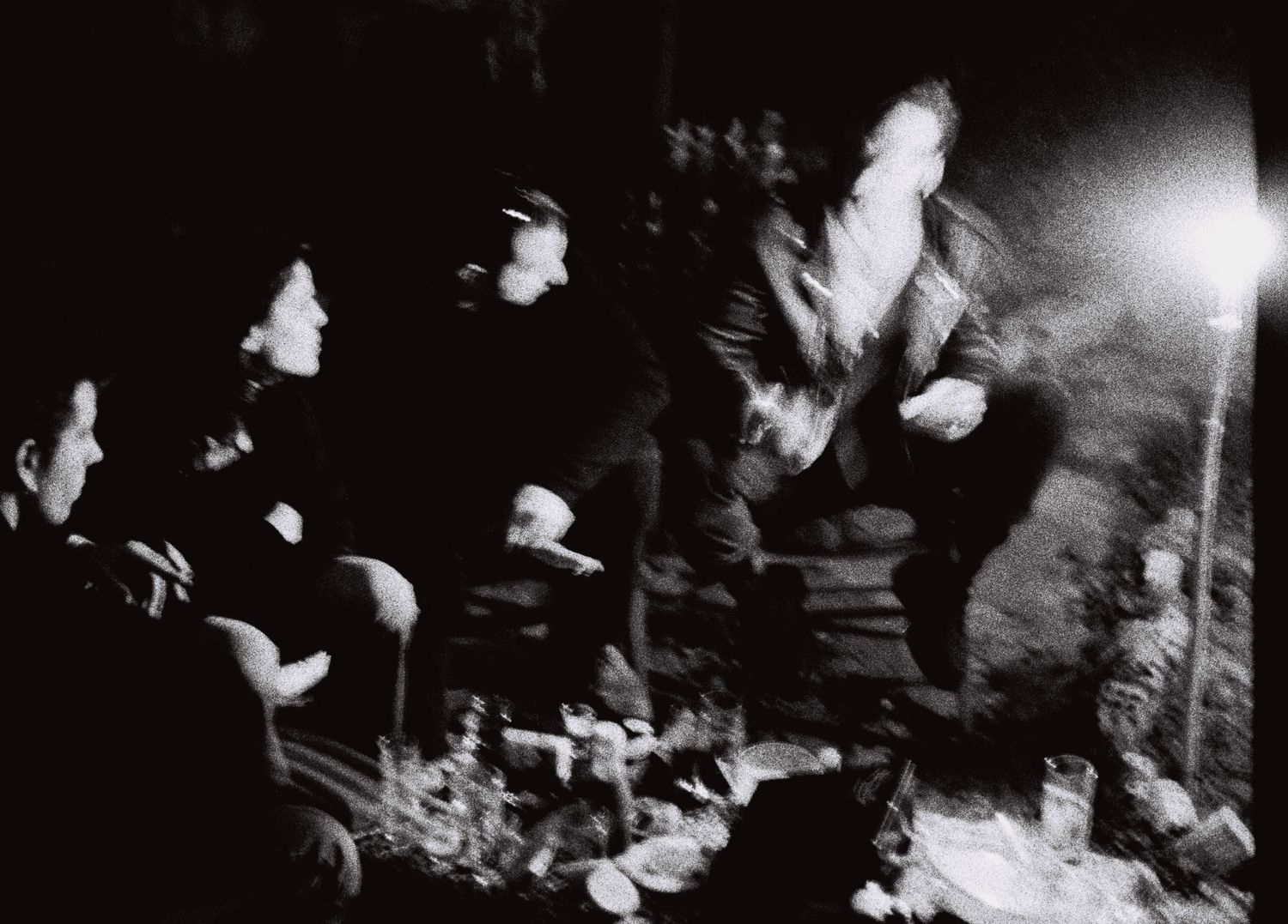A blurry black and white photo of people at a concert with a performer jumping on stage.