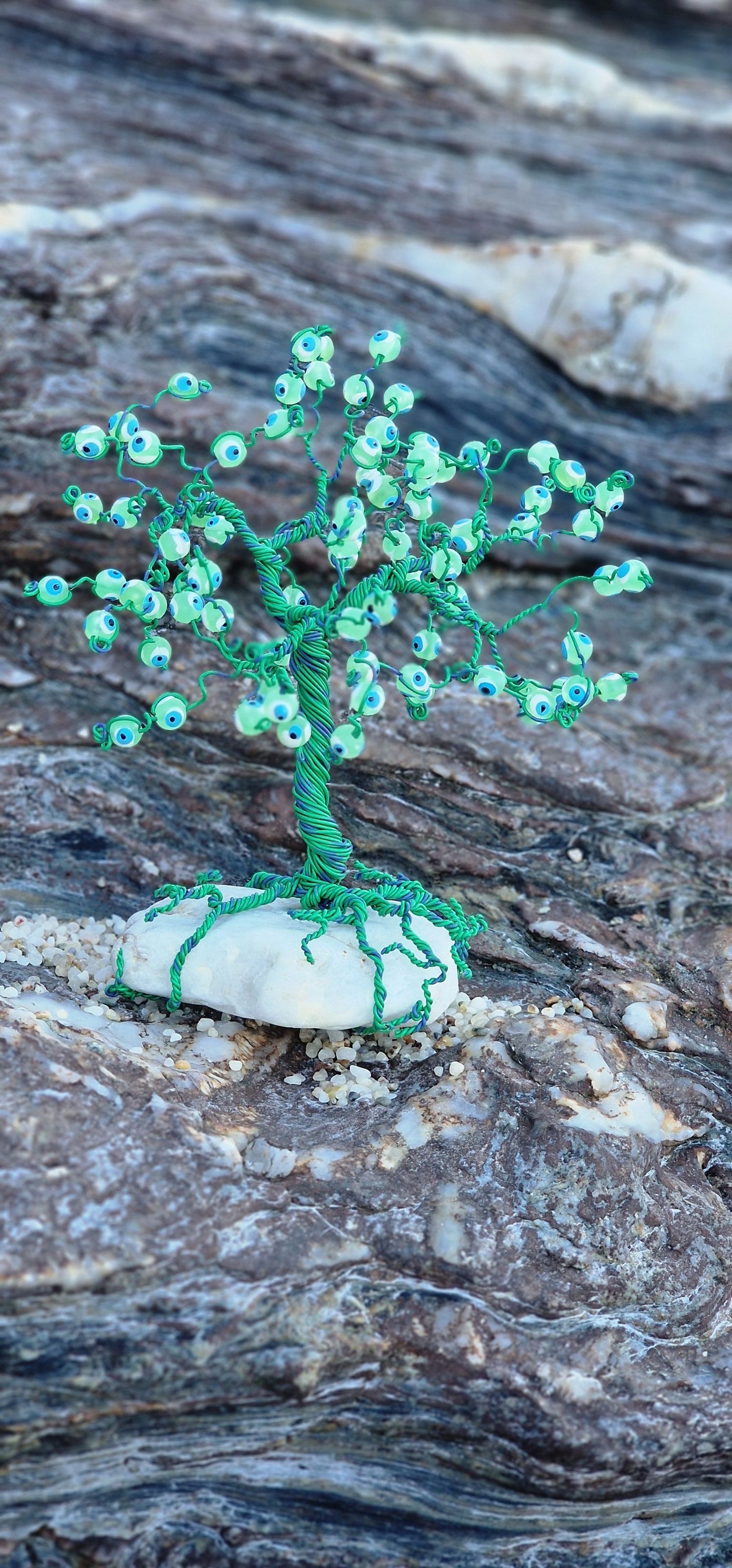 Handcrafted green beaded wire tree sculpture with intricate branches mounted on a white stone base.