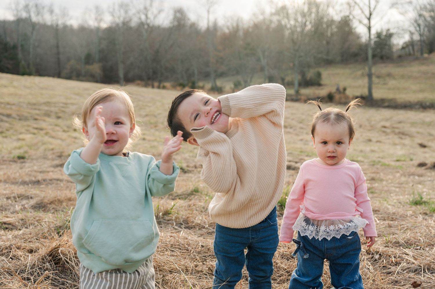 A group of children playing together in a grassy field on a sunny autumn day.